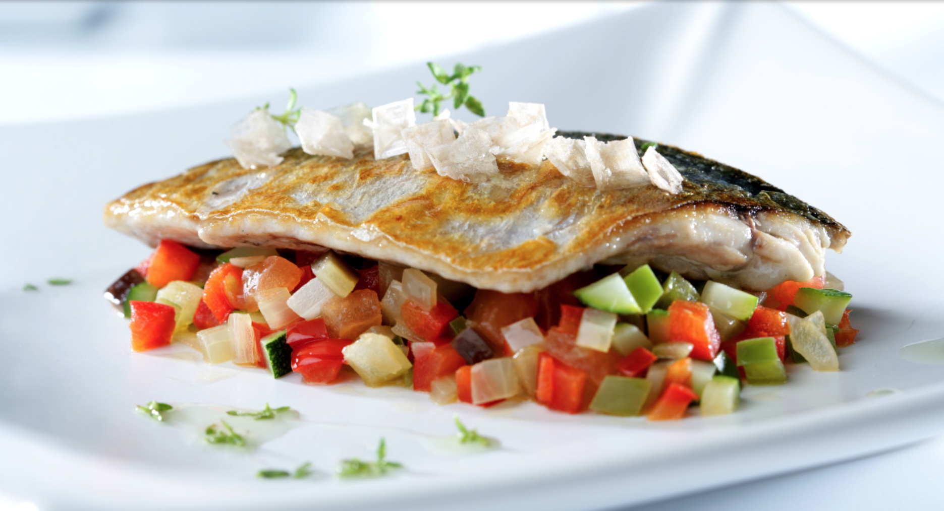 Lubina a la plancha sobre aliño de verduras.